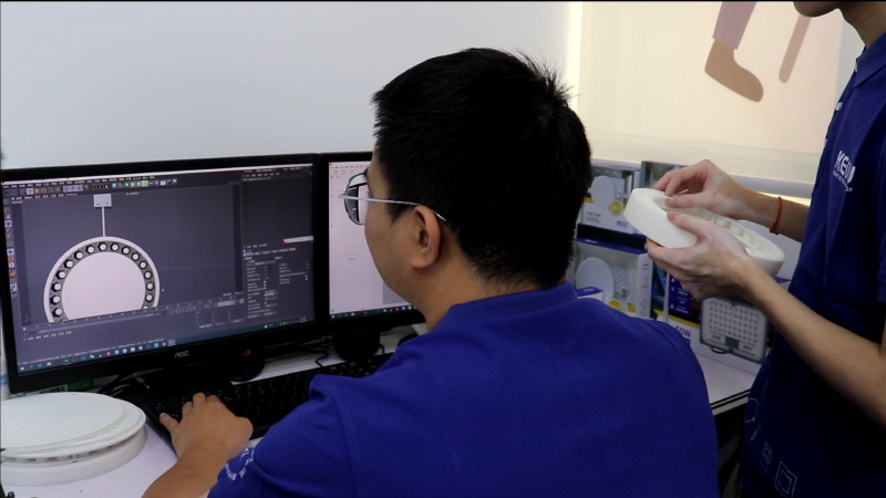 Operations Team-KEOU R&D engineer designs LED light 3D models on computer with physical prototype